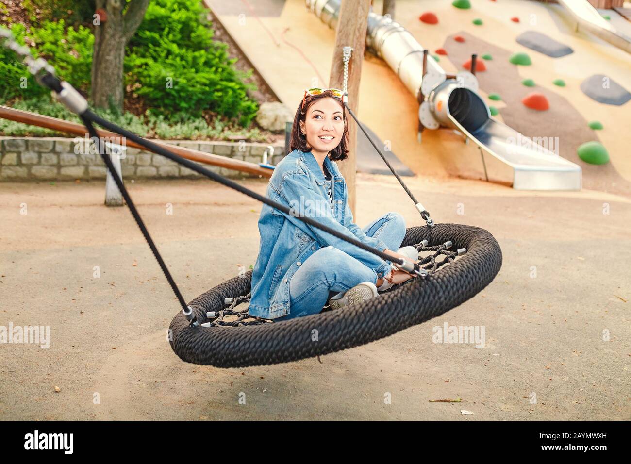 young woman having fun on a seesaw swing at urban playground Stock Photo