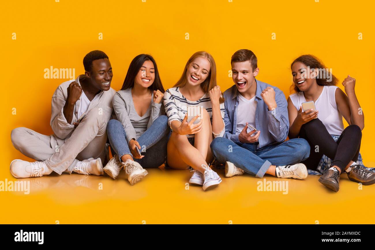 Happy friends celebrating success, looking at mobile phone screen Stock Photo