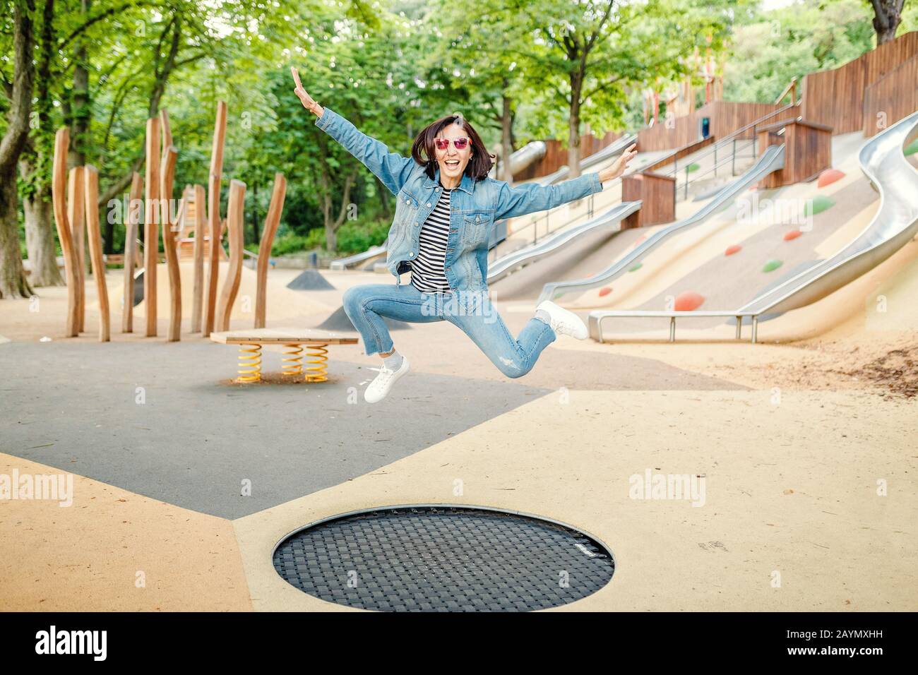 Happy girl having fun jumping on a trampoline at the outdoor modern ...