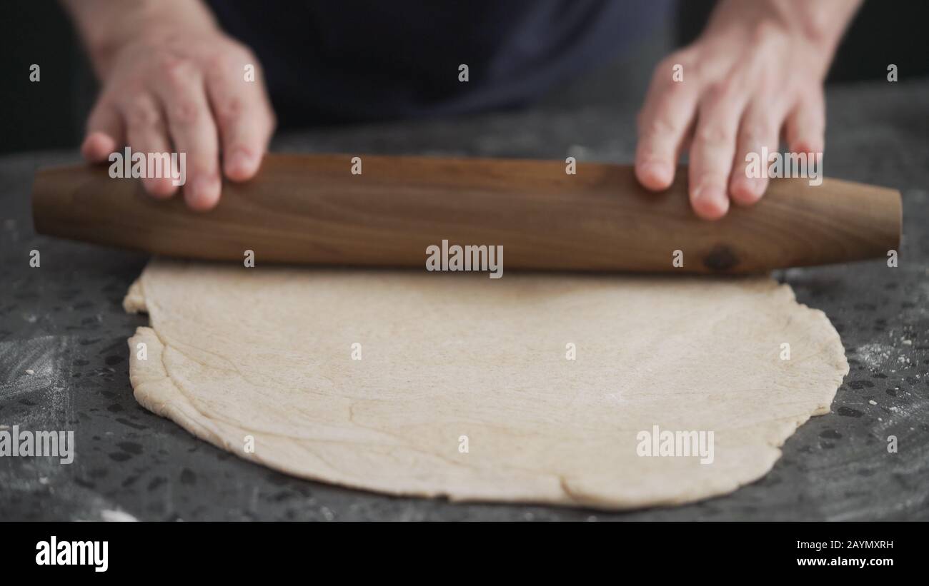 man rolling dough on concretre countertop, wide space Stock Photo