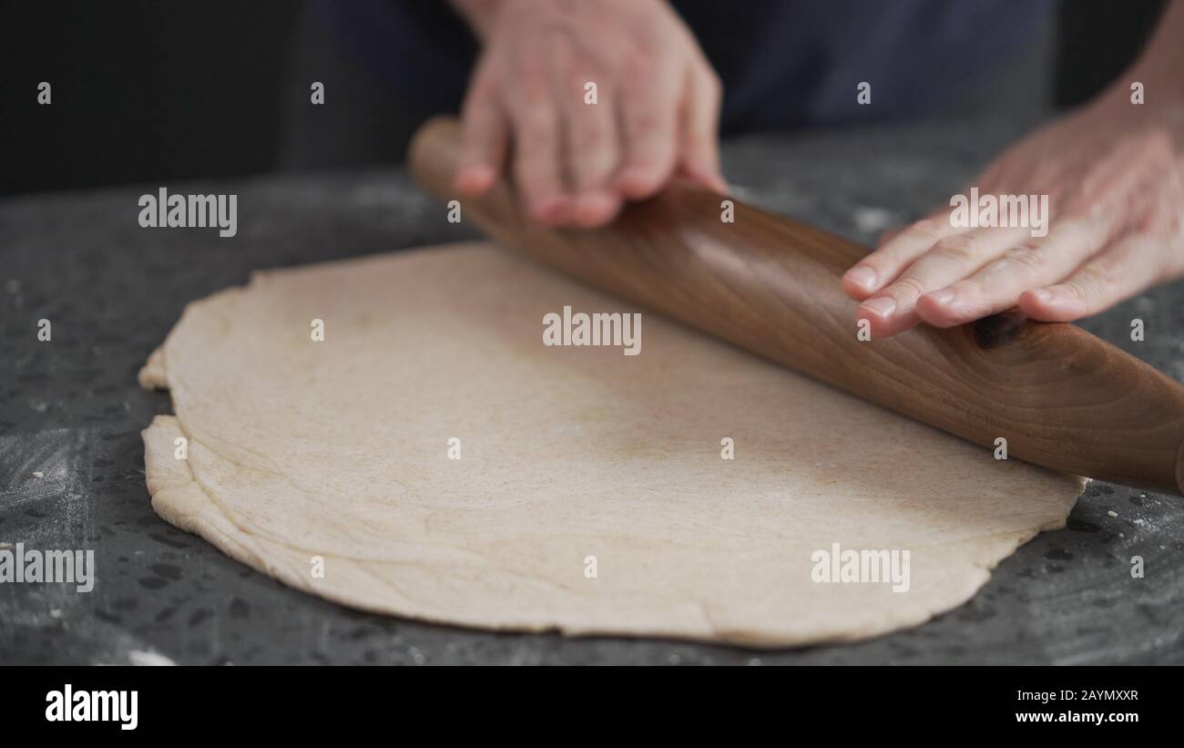 man rolling dough on concretre countertop, wide space Stock Photo