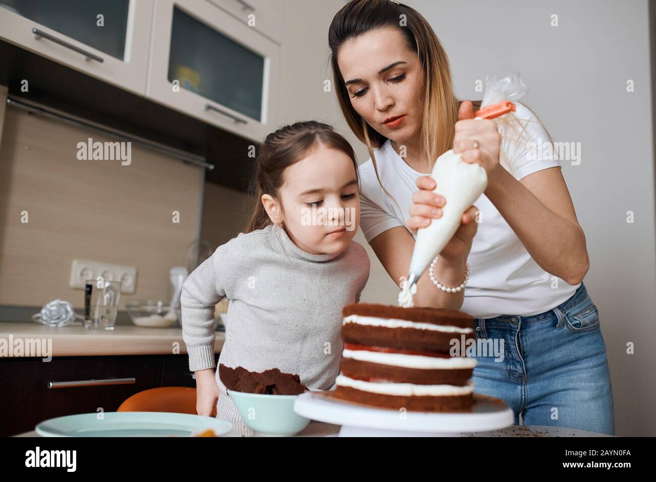 serious little girl and her sisiter preparing cake for their mother, concentration, effort, close up photo Stock Photo