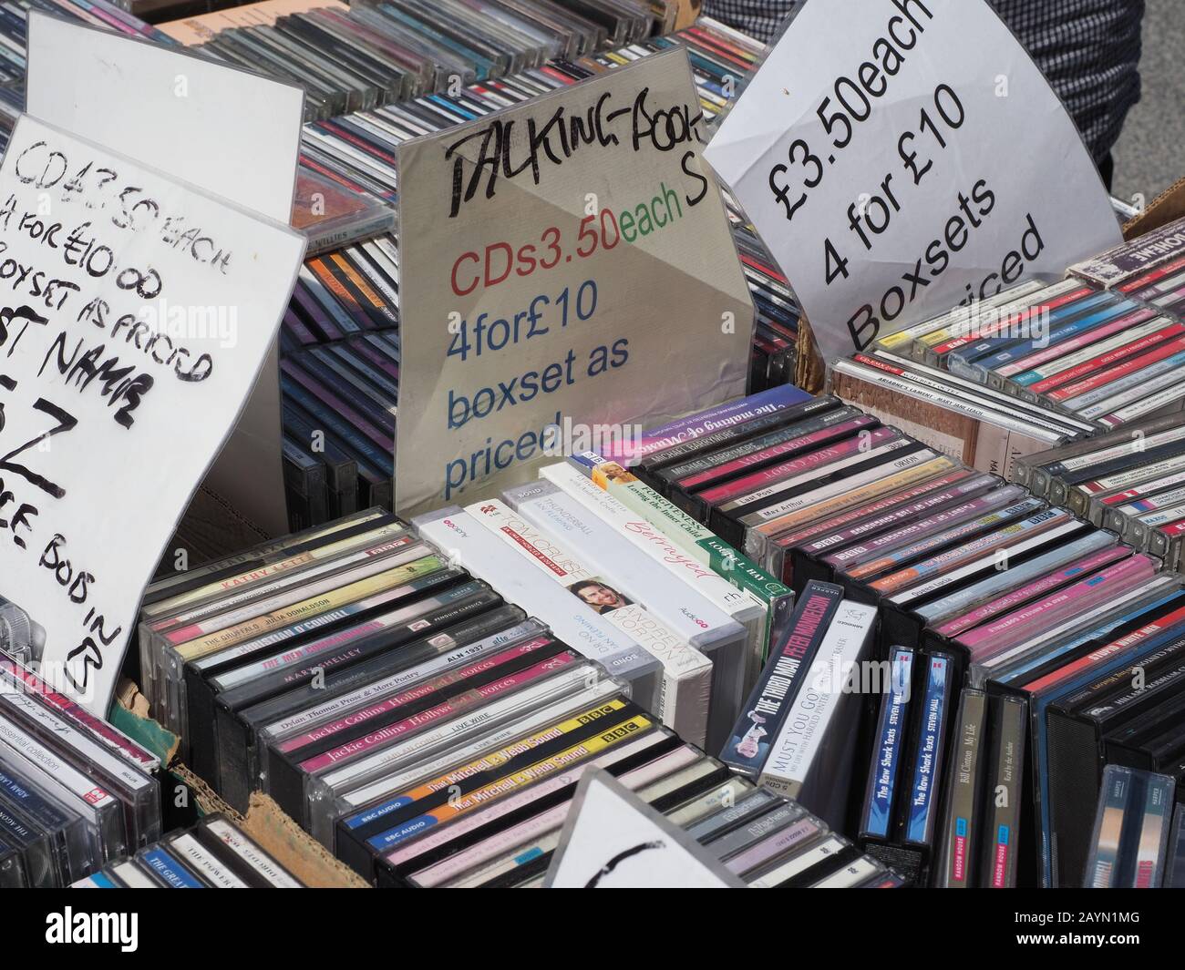 close up of a stack of various compact discs, cds for sale on a stall