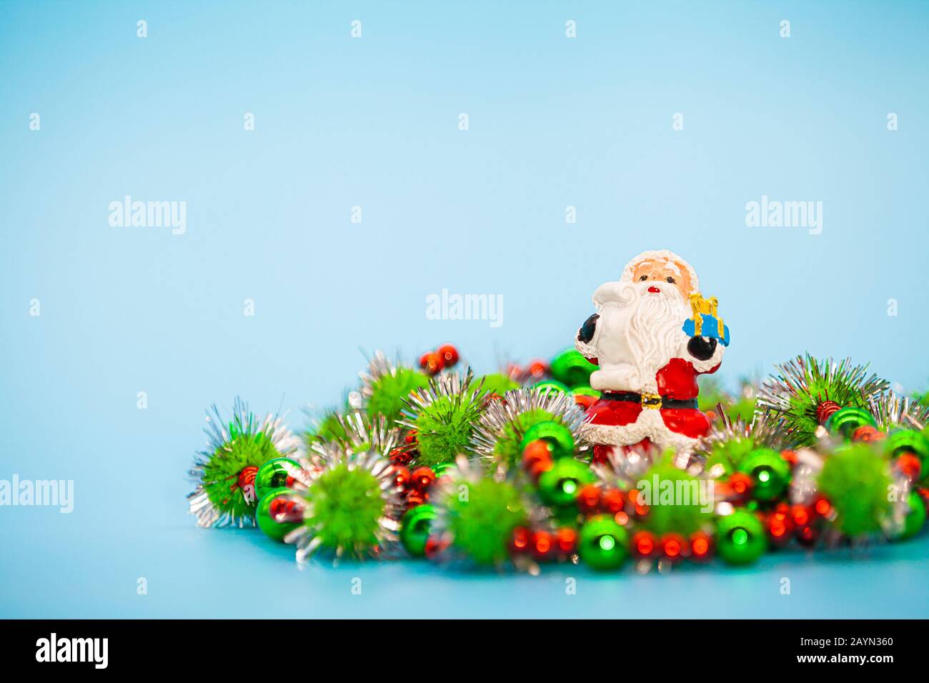 Ornamental Santa clause sat within Christmas beads and tinsel against a white background. Stock Photo
