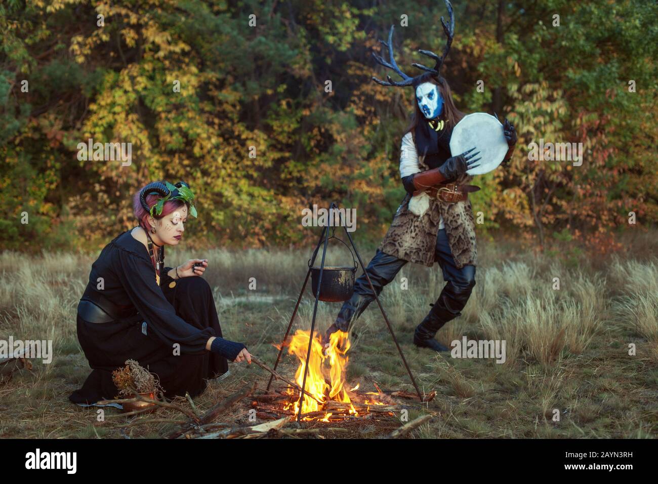 Shamans conjure in the forest. They are preparing a magic potion at the stake. Stock Photo