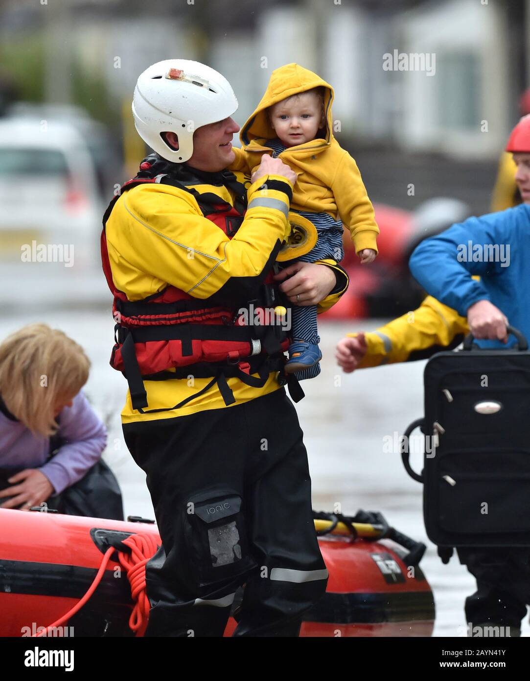 One-year-old Blake is carried by a rescue worker as emergency services continue to take families to safety, after flooding in Nantgarw, Wales, as Storm Dennis hit the UK. Stock Photo