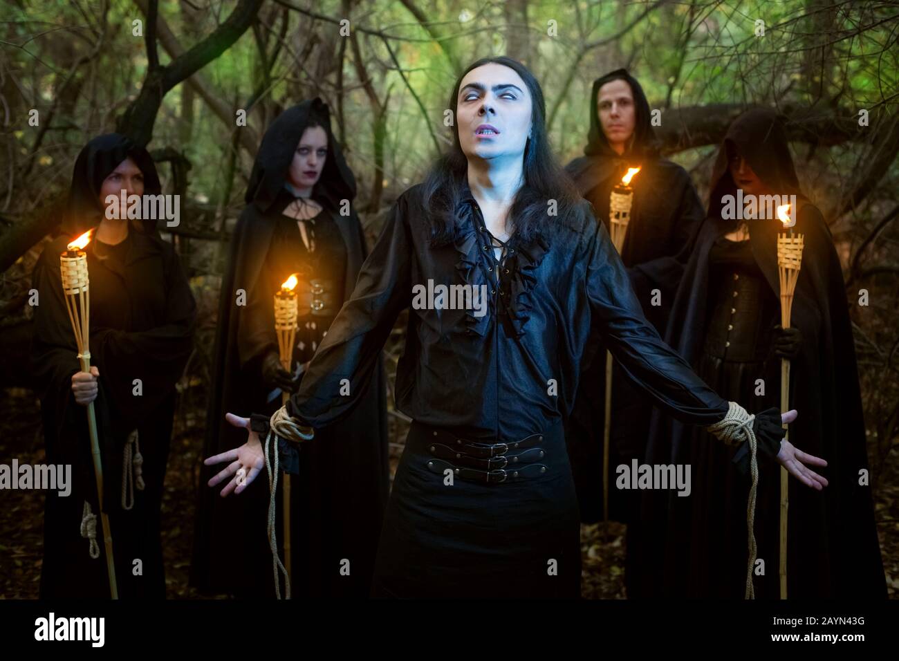 Warlocks in black cloaks spend a magical rite of the man in the woods. Stock Photo