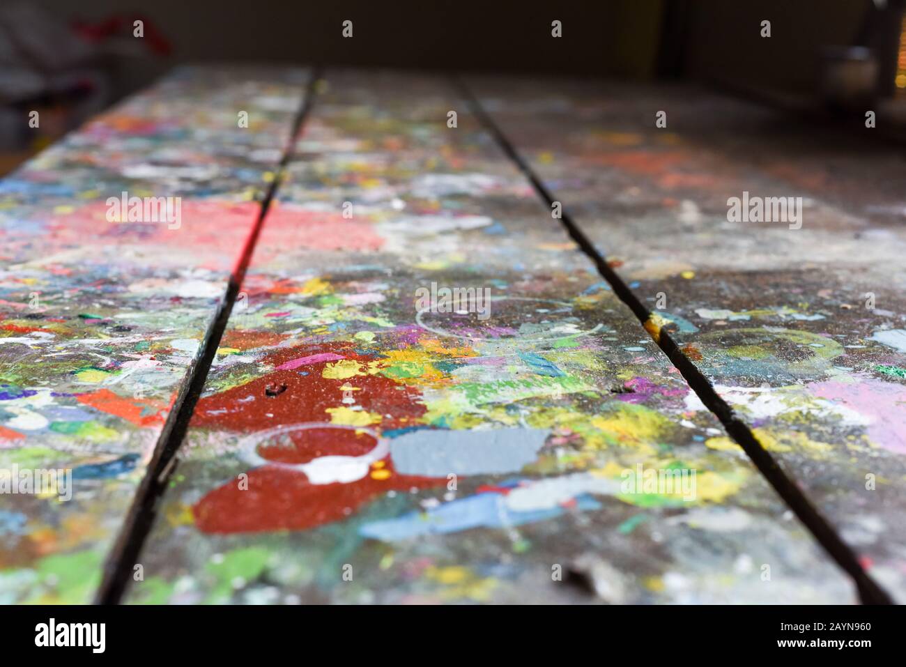 Artists workshop or studio bench covered with splattered paint built up in authentic texture on painted surface Stock Photo