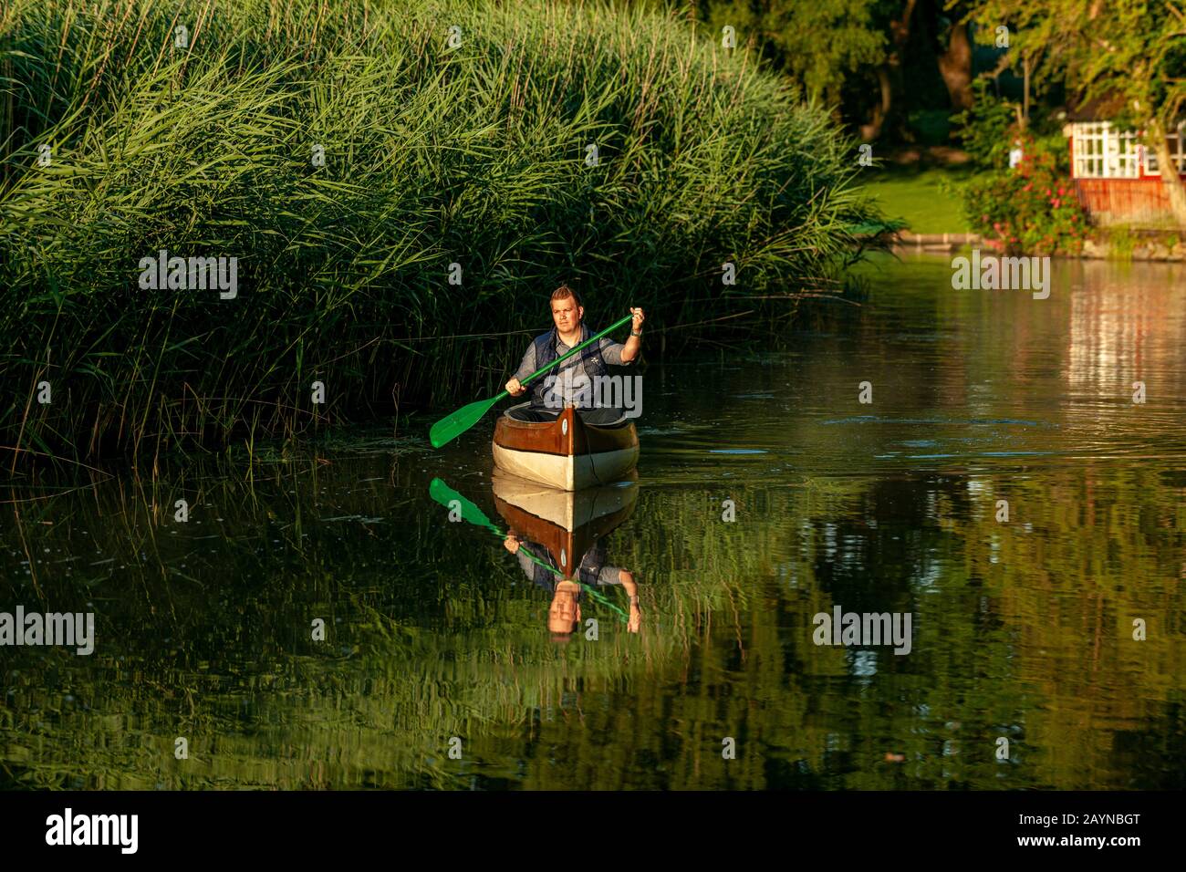 a man in a canoe is riding in the morning on a river in golden light Stock Photo