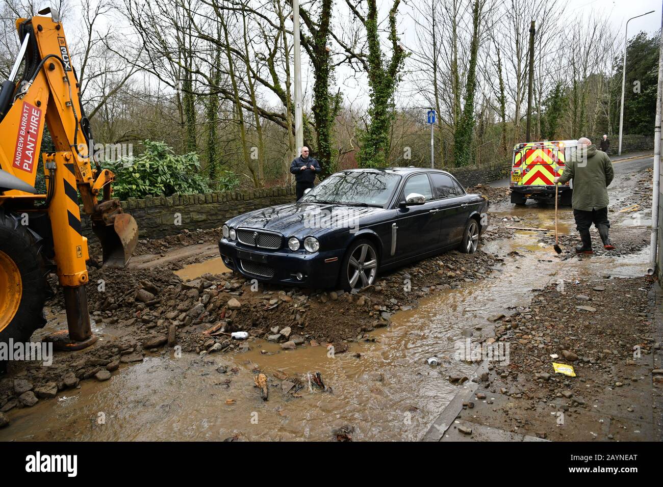 A Digger Is Used To Clear Debris From A Trapped Car Carried By Floodwater From The Road Outside The Aberdare Hotel In Mountain Ash Wales As Storm Dennis Hit The Uk Stock