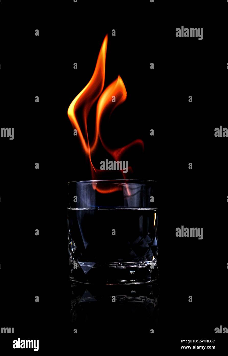 Glass with vodka and fire flame on black background Stock Photo