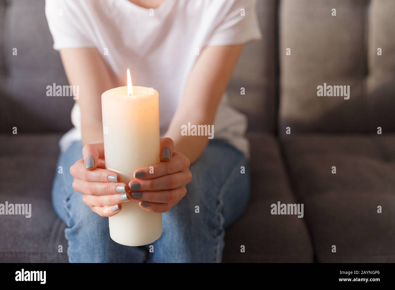 woman holding burning candle in her hands Stock Photo