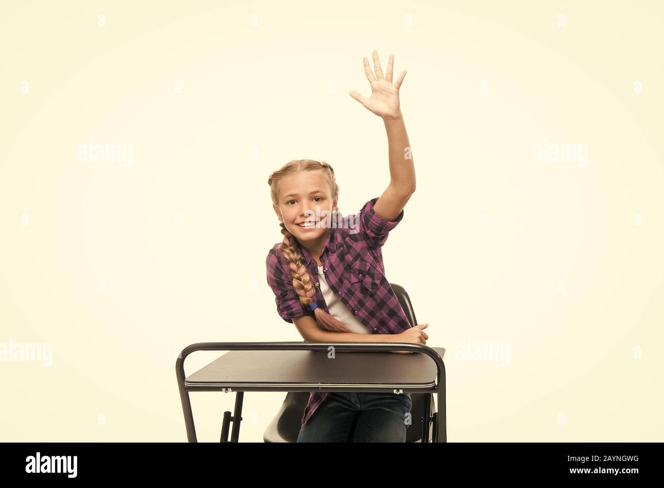 She is a bright student. Small girl student raising hand isolated on white. Little student reciting lesson in class. Cute lyceum student sitting at desk. Stock Photo