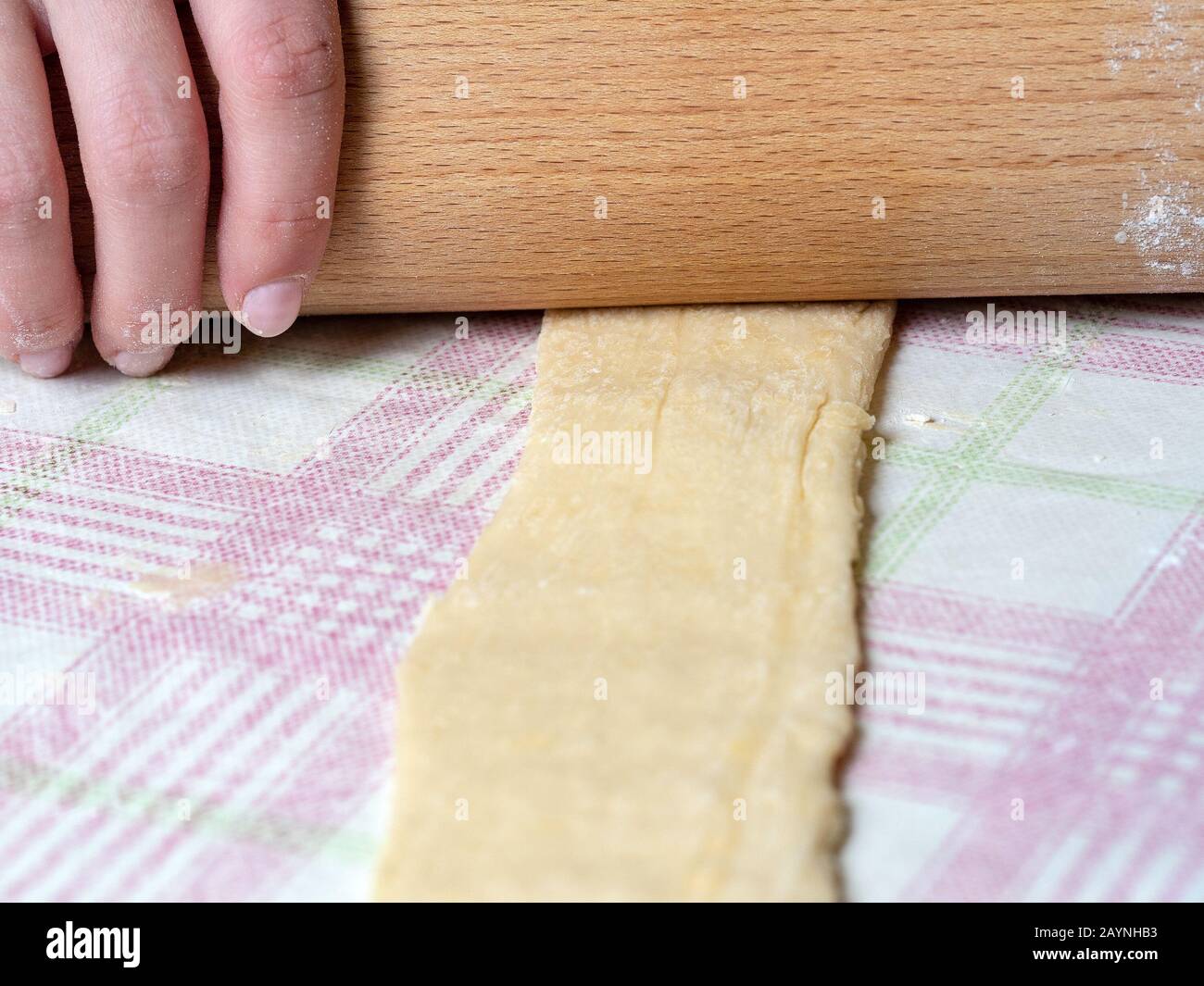the Baker rolls the dough into strips on the kitchen table, sprinkled