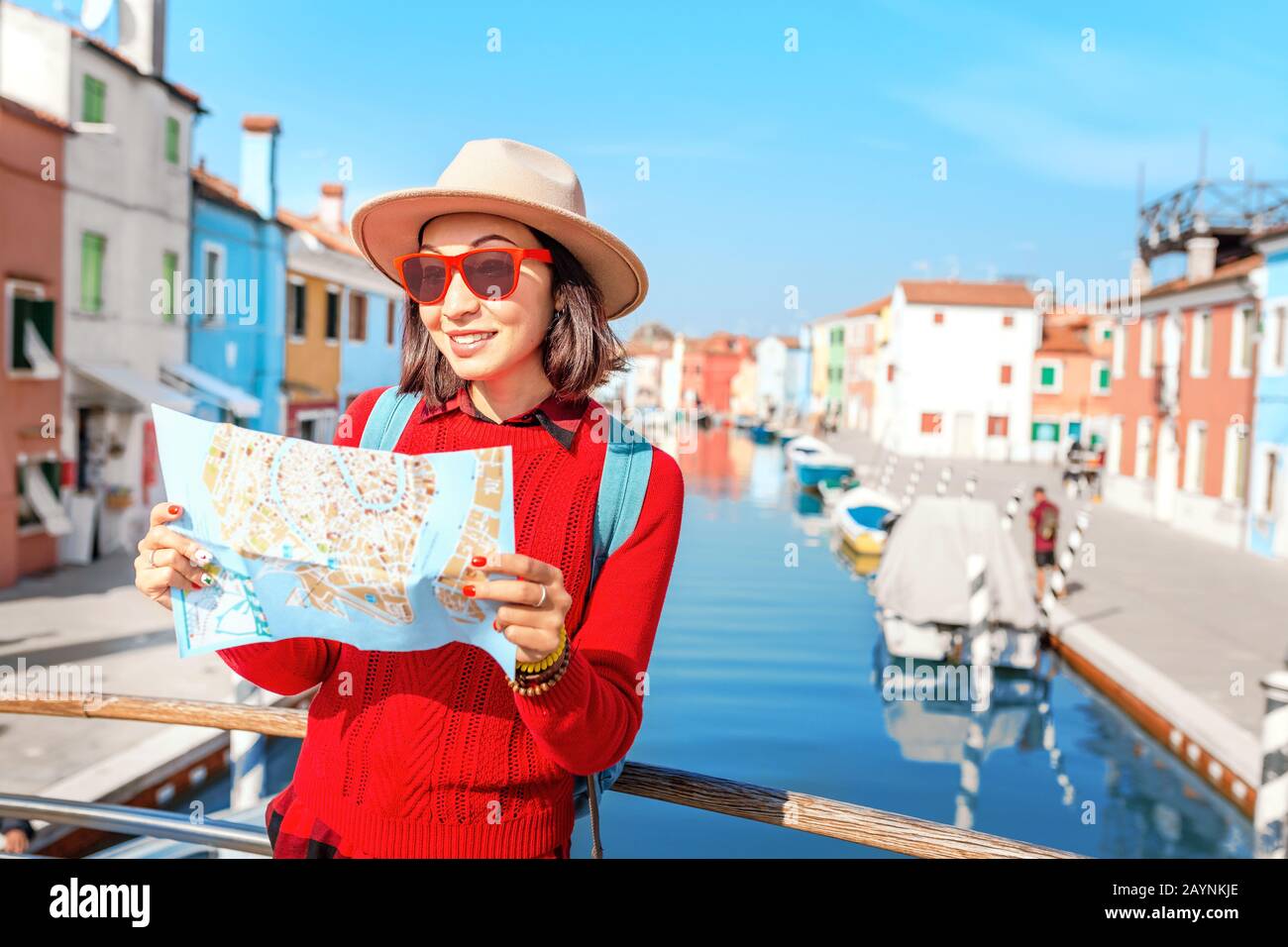 young happy traveler woman looking at the tourist map among colorful houses on Burano island, Venice. Tourism in Italy concept Stock Photo