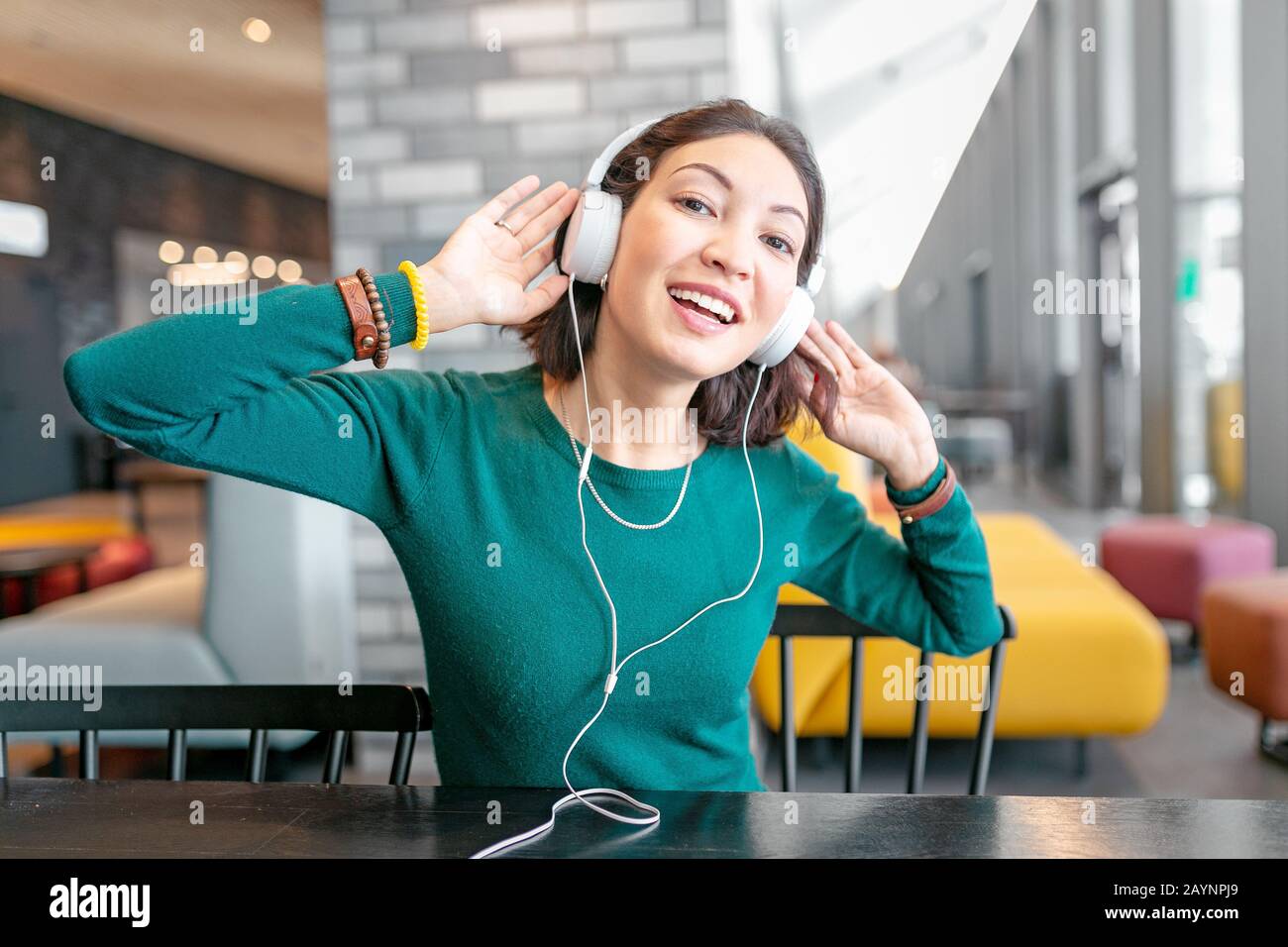 Happy asian woman enjoying the music by headphones and relax in hotel hall or cafe Stock Photo