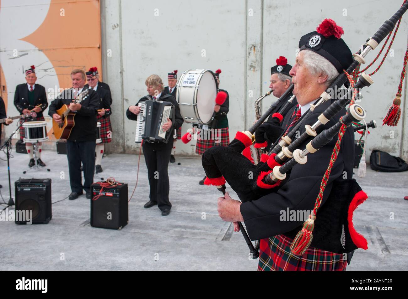 A bagpipe band is playing for a cruise ship in the port of Dunedin on