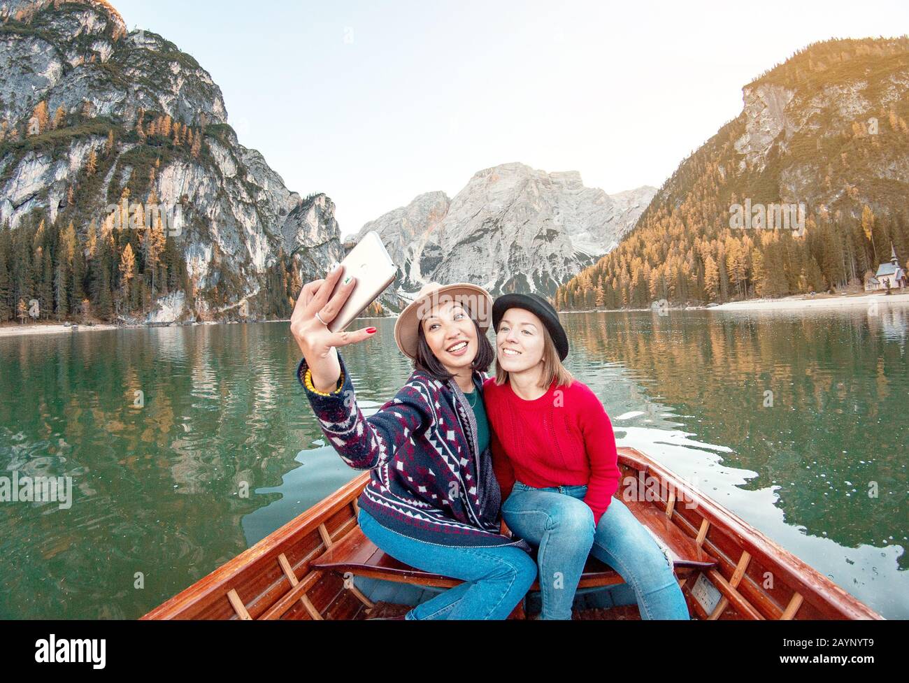Two happy woman friends making selfie photo on the boat or canoe cruise tour on lago Di Braies lake in Italian Dolomites Alps Stock Photo