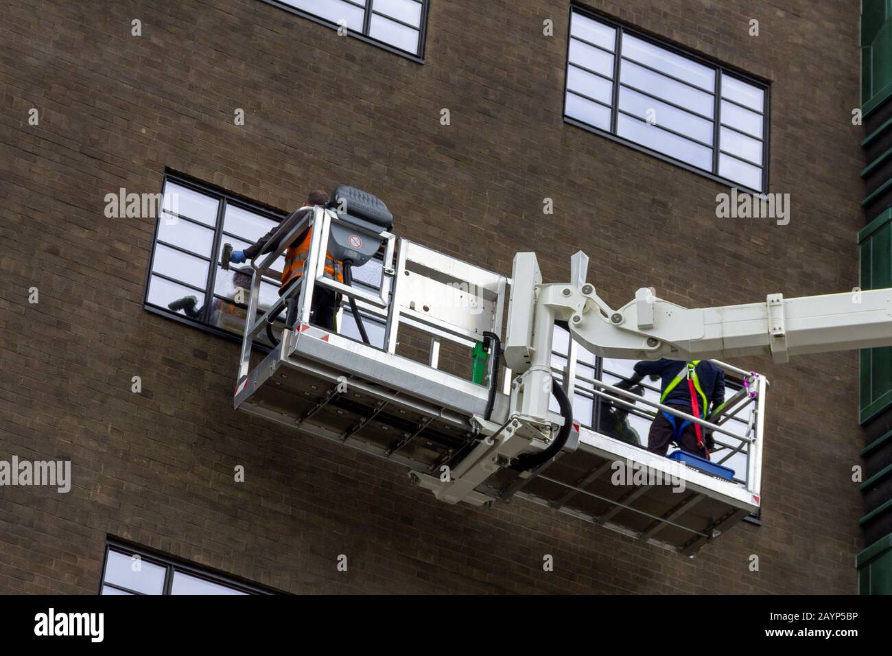 A close up portrait of two window washers, using a crane to get to the