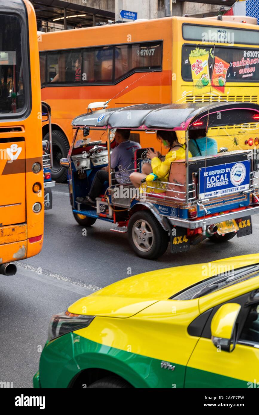 tuk tuk and taxi cabs with busses and public transport in bangkok, thailand on the busy city centre streets at rush hour. Stock Photo