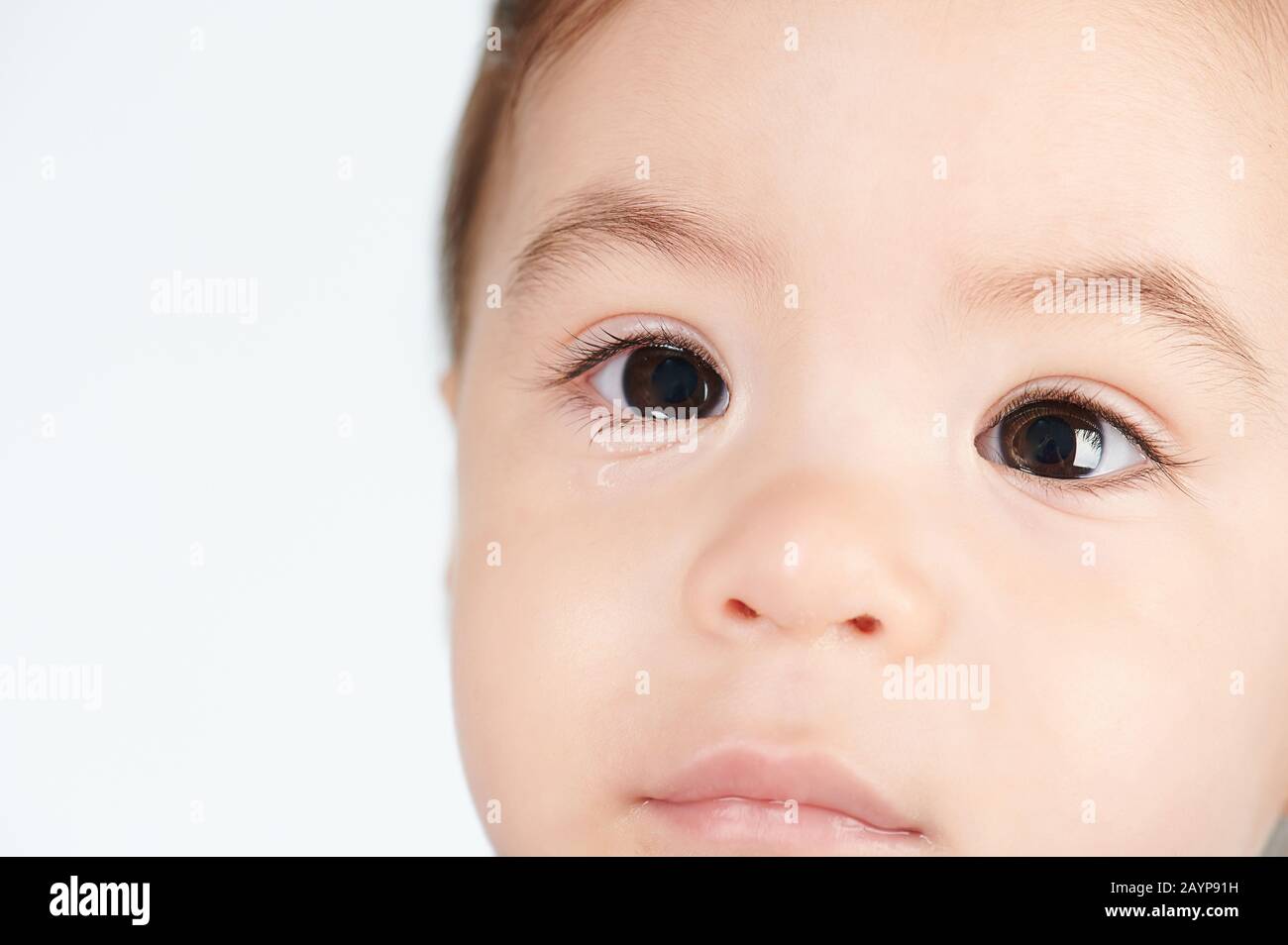 Baby girl with wet eyes close up view isolated on white background Stock Photo