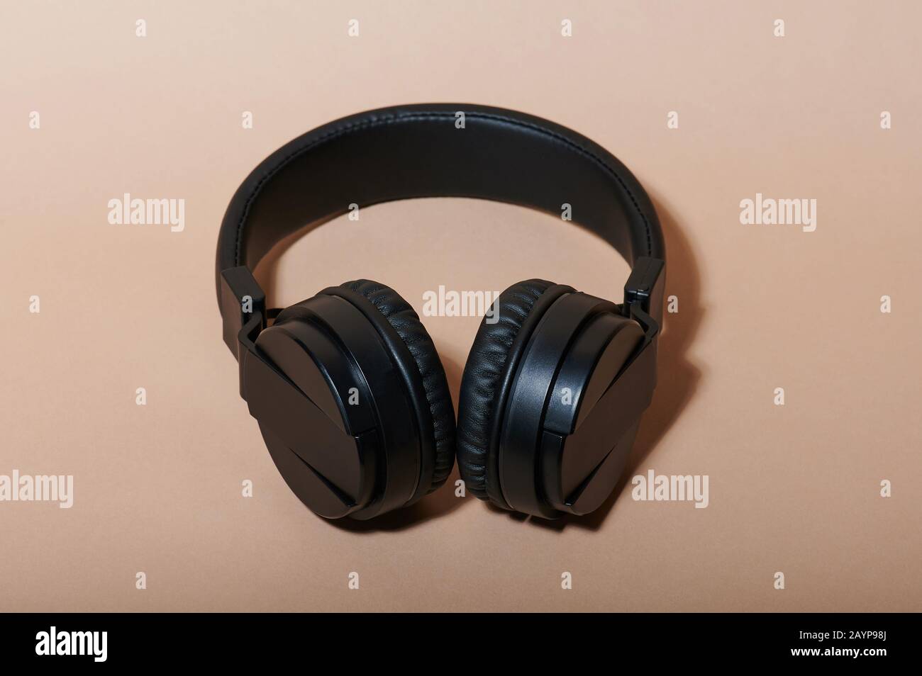 Close up of black headphones lay on beige color background Stock Photo