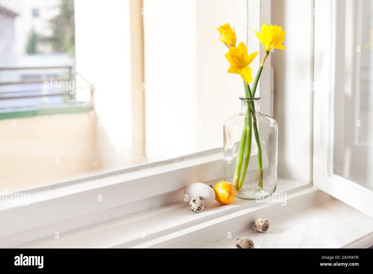 minimalistic easter decoration on windowsill easter bells, daffodils in old building easter eggs on windowsill light background, with copy space Stock Photo