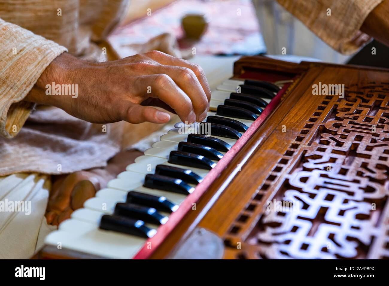 Closeup of shamanic hands pressing harmonium keys playing sacred kirtan