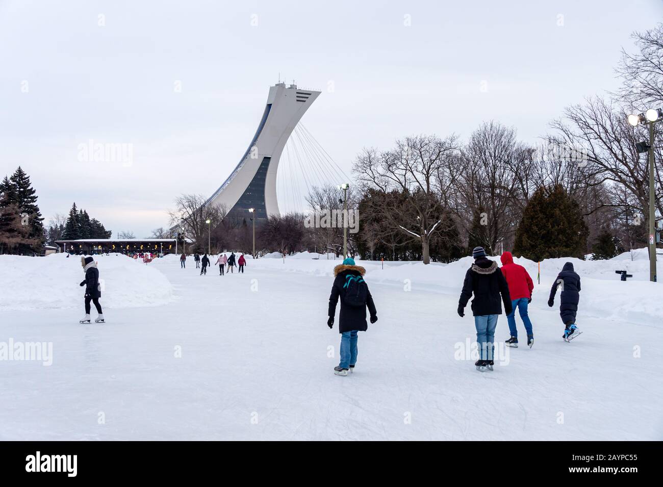 Montreal, CA - 15 February 2020: People  ice skating at the Park Maisonneuve ice rink with olympic Stadium Tower in background. Stock Photo