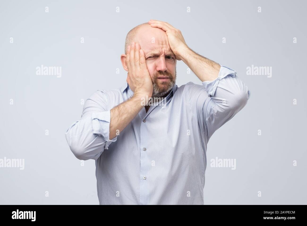 Mature caucasian man having headache feeling tired after hard day. Studio shot. Negative facial human emotion. Stock Photo