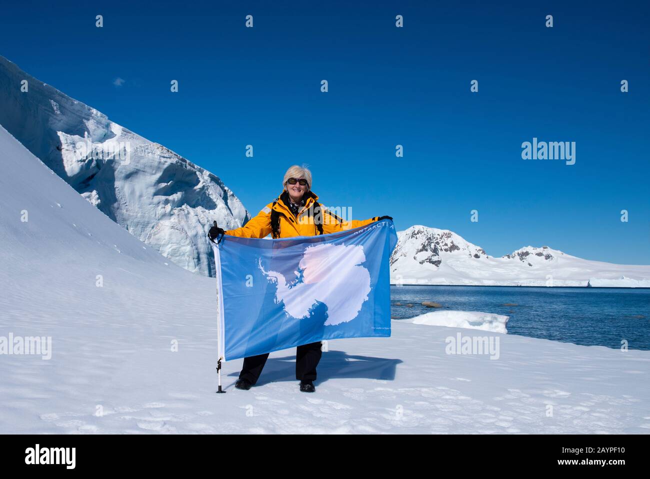 Antarctica, Antarctic peninsula, Northern Gerlache, Charlotte Bay. Expedition photographer and adventure traveler, Cindy Miller Hopkins, with flag. Stock Photo