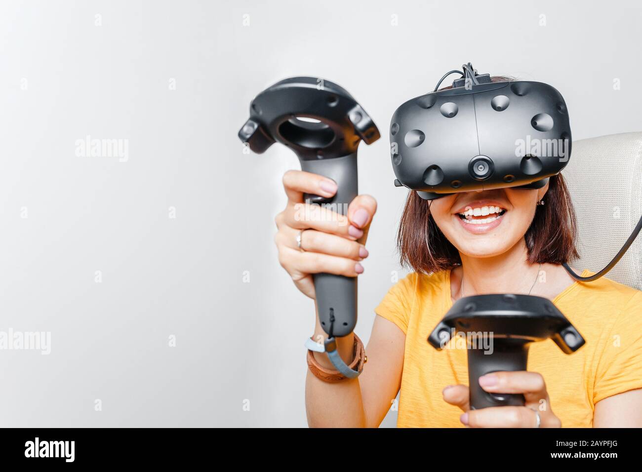 Happy woman with virtual reality headset and joystick playing VR games Stock Photo