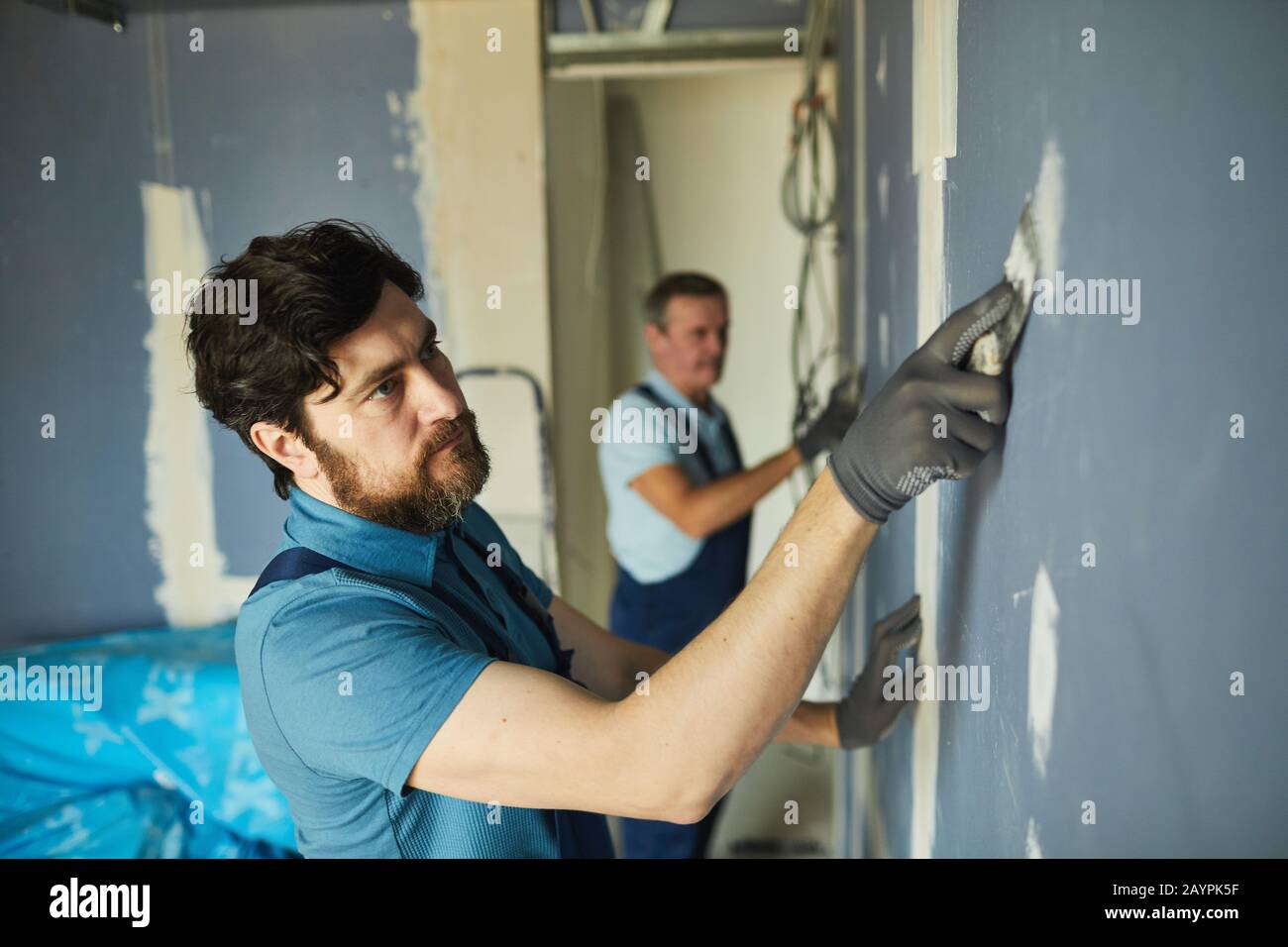 High angle portrait of two construction workers building dry wall while ...