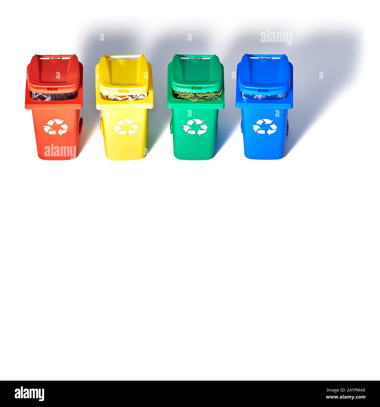 Four color coded recycle bins, isometric projection on geometric rainbow paper background with copy-space. Recycling sign on the bins - red, blue, yel Stock Photo