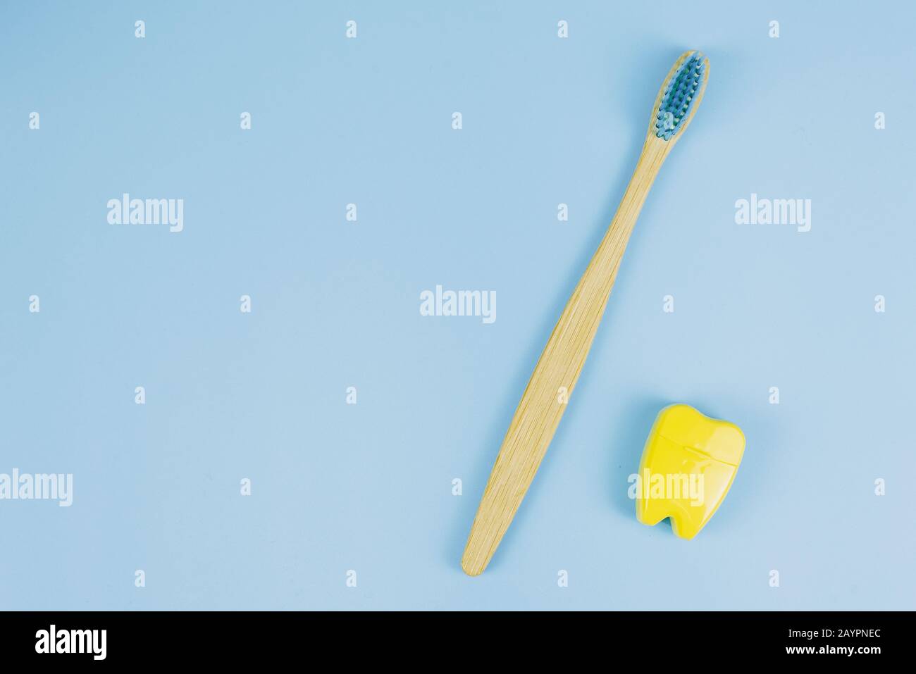Bamboo wooden brush and dental floss in the form of a tooth on a blue ...