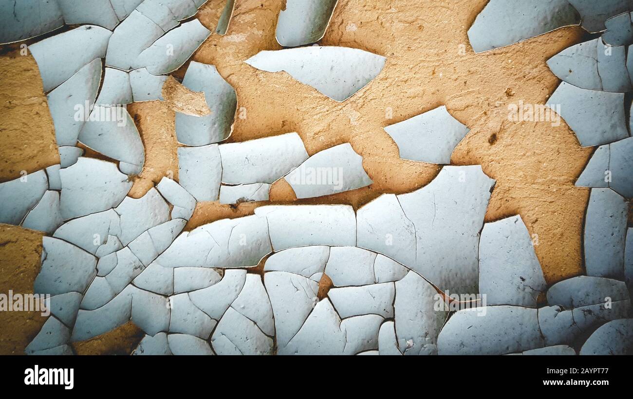 background old pieces of blue cracked and peeling paint on a brown wall Stock Photo