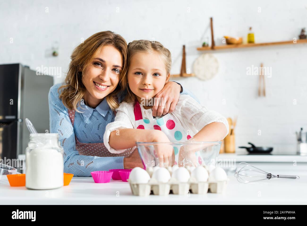 Selective focus of mother and daughter preparing dough for cupcakes in kitchen Stock Photo