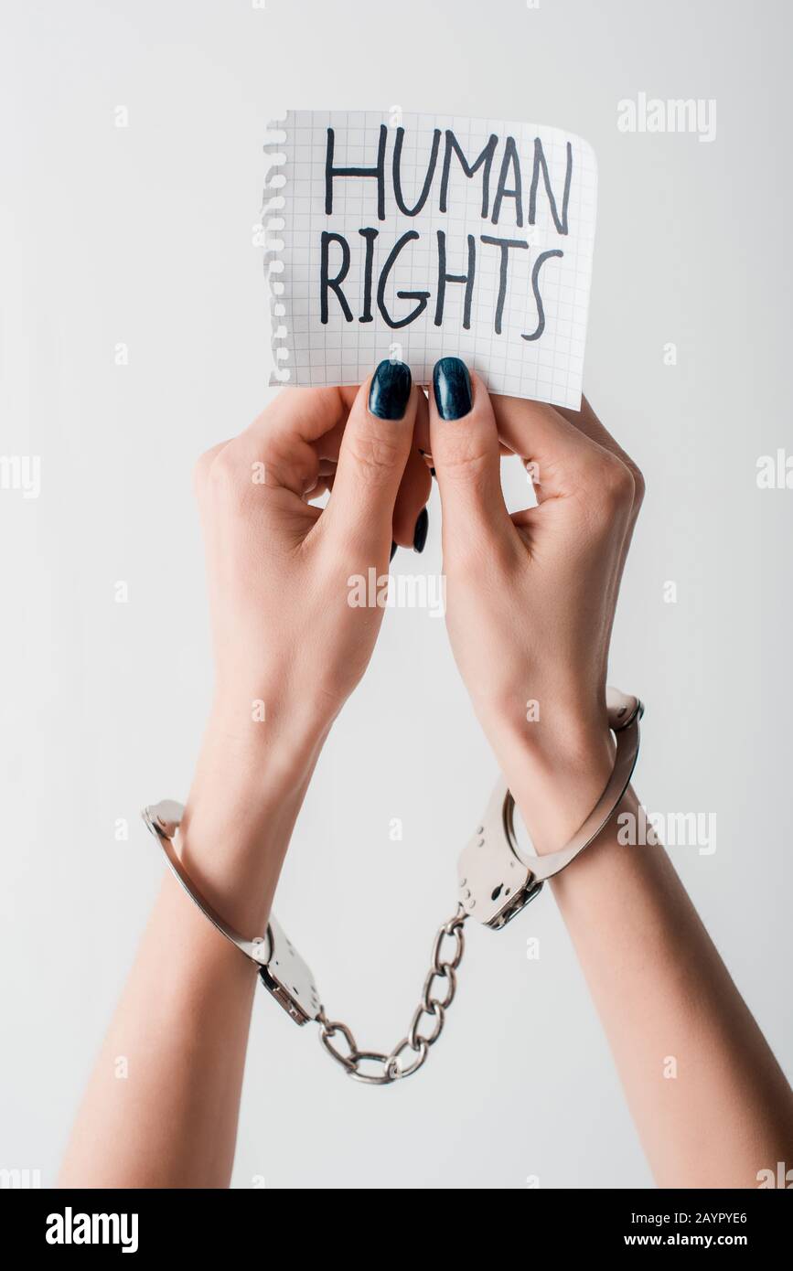 cropped view of handcuffed woman holding paper with human rights lettering isolated on white Stock Photo