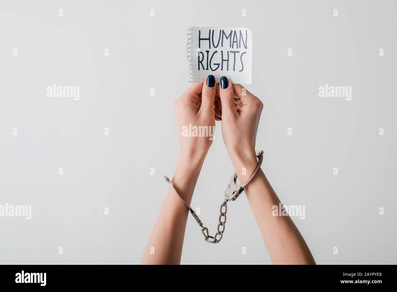 cropped view of young woman with handcuffs on hands holding paper with human rights lettering isolated on white Stock Photo