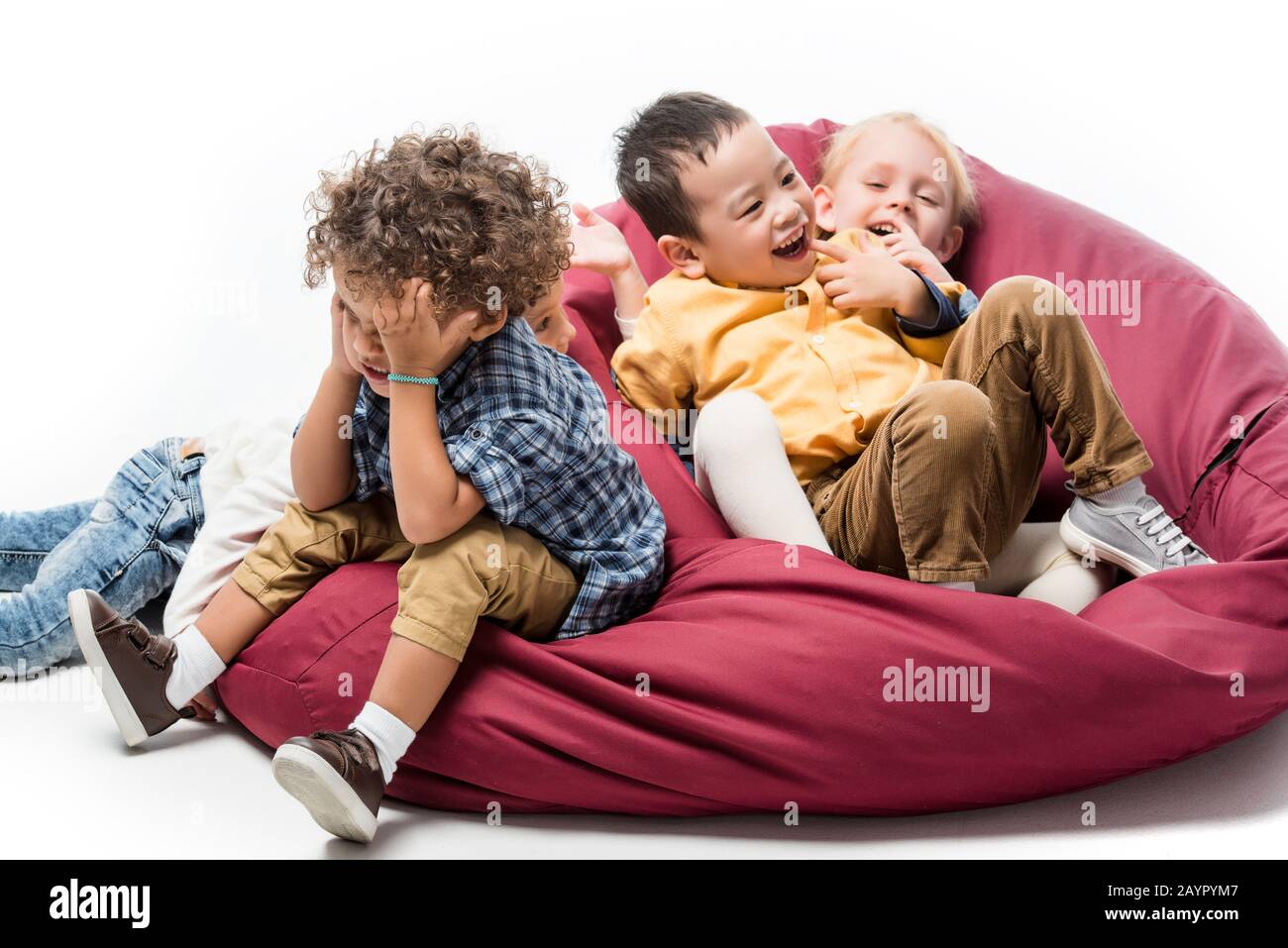 multicultural kids playing together on red bin bag chair on white Stock