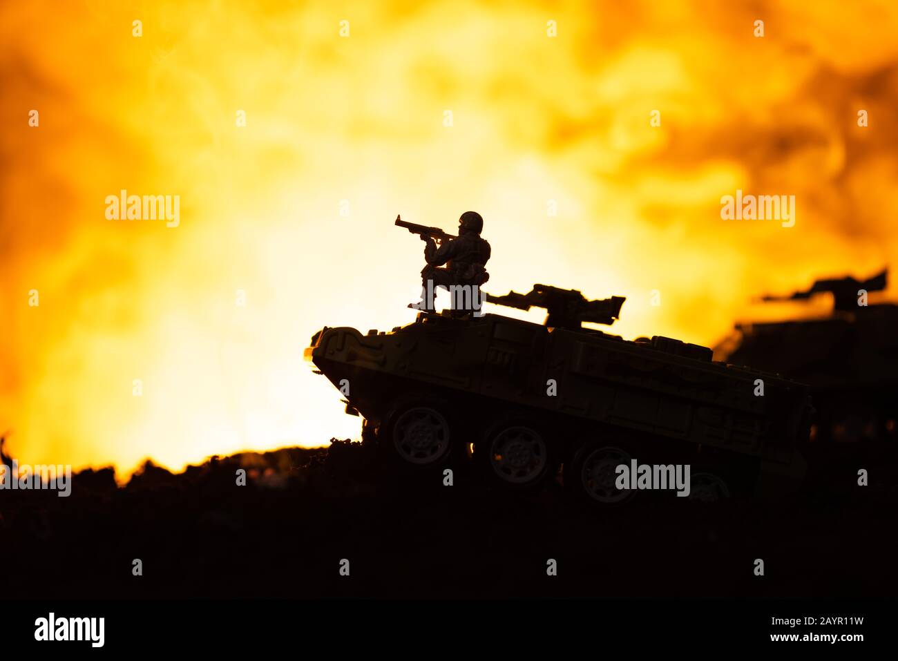 Silhouette of toy soldier on tank with fire at background, battle scene Stock Photo