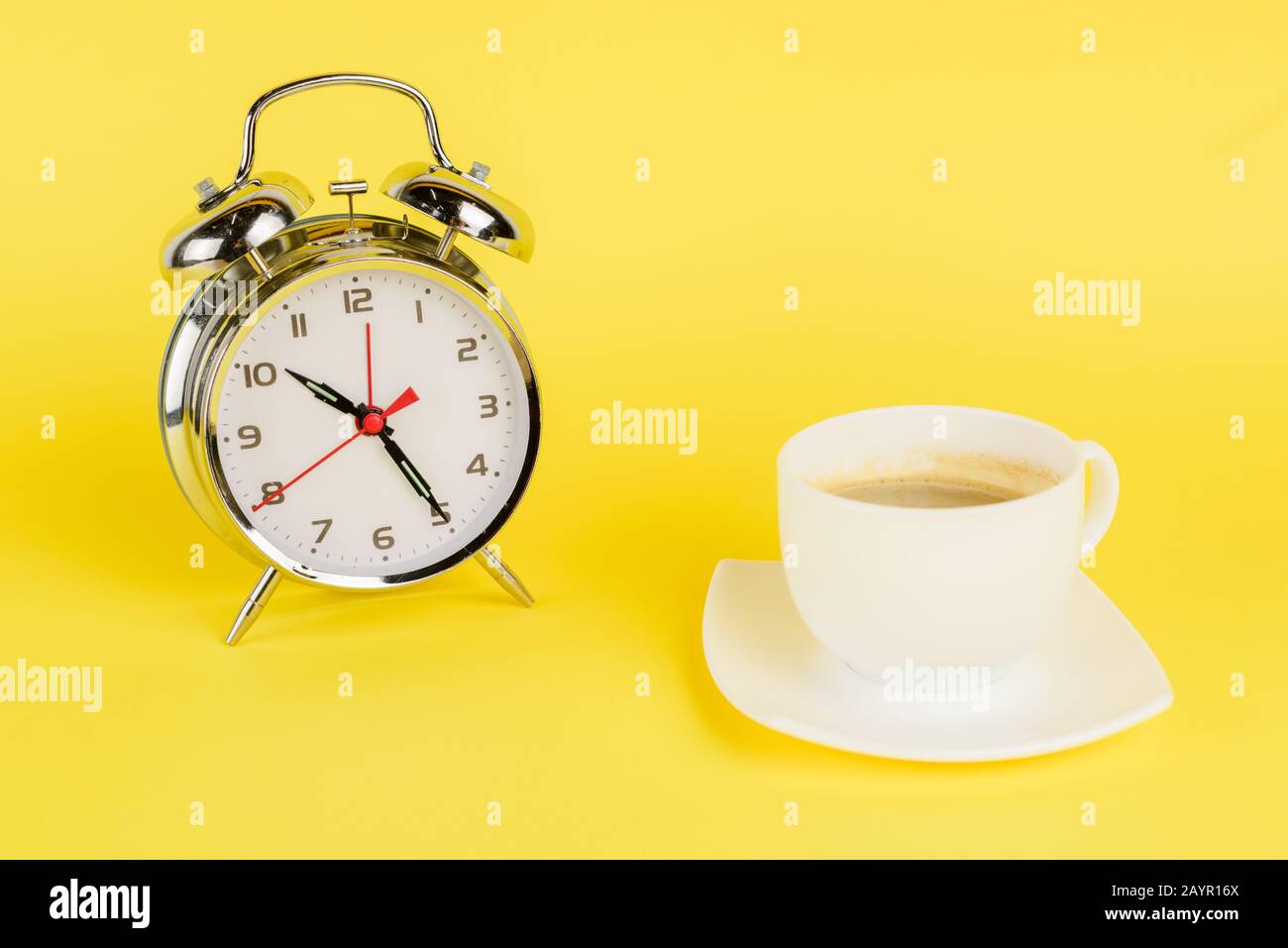 https://c8.alamy.com/comp/2AYR16X/silver-alarm-clock-and-cup-of-coffee-on-yellow-background-2AYR16X.jpg