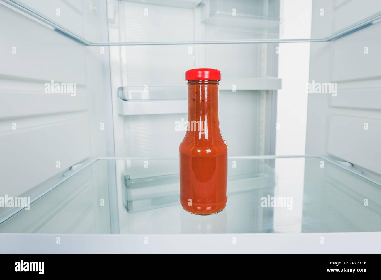 Bottle of tomato sauce in fridge with open door isolated on white,stock