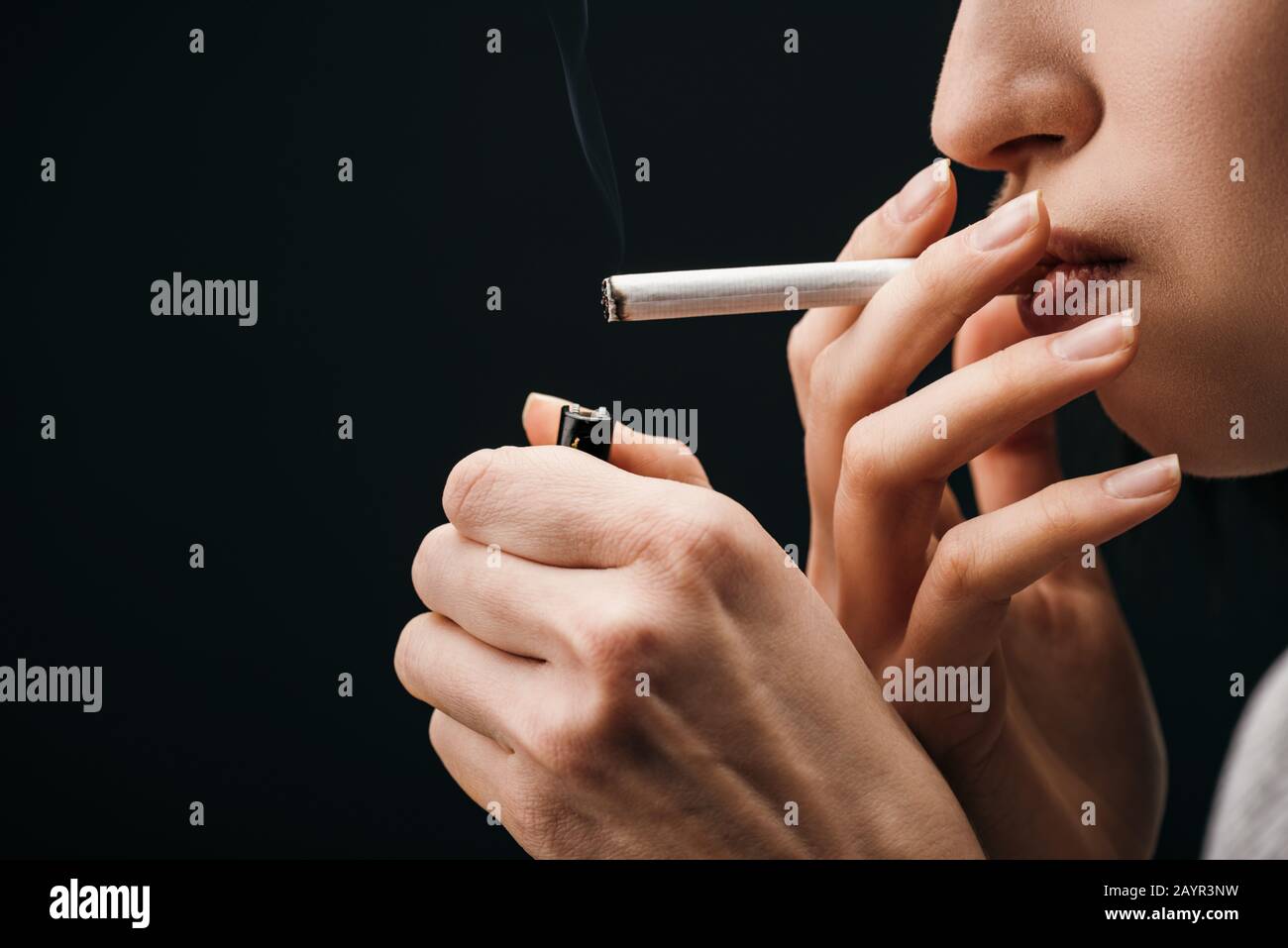 Side view of young woman lighting cigarette with lighter isolated on black  Stock Photo - Alamy