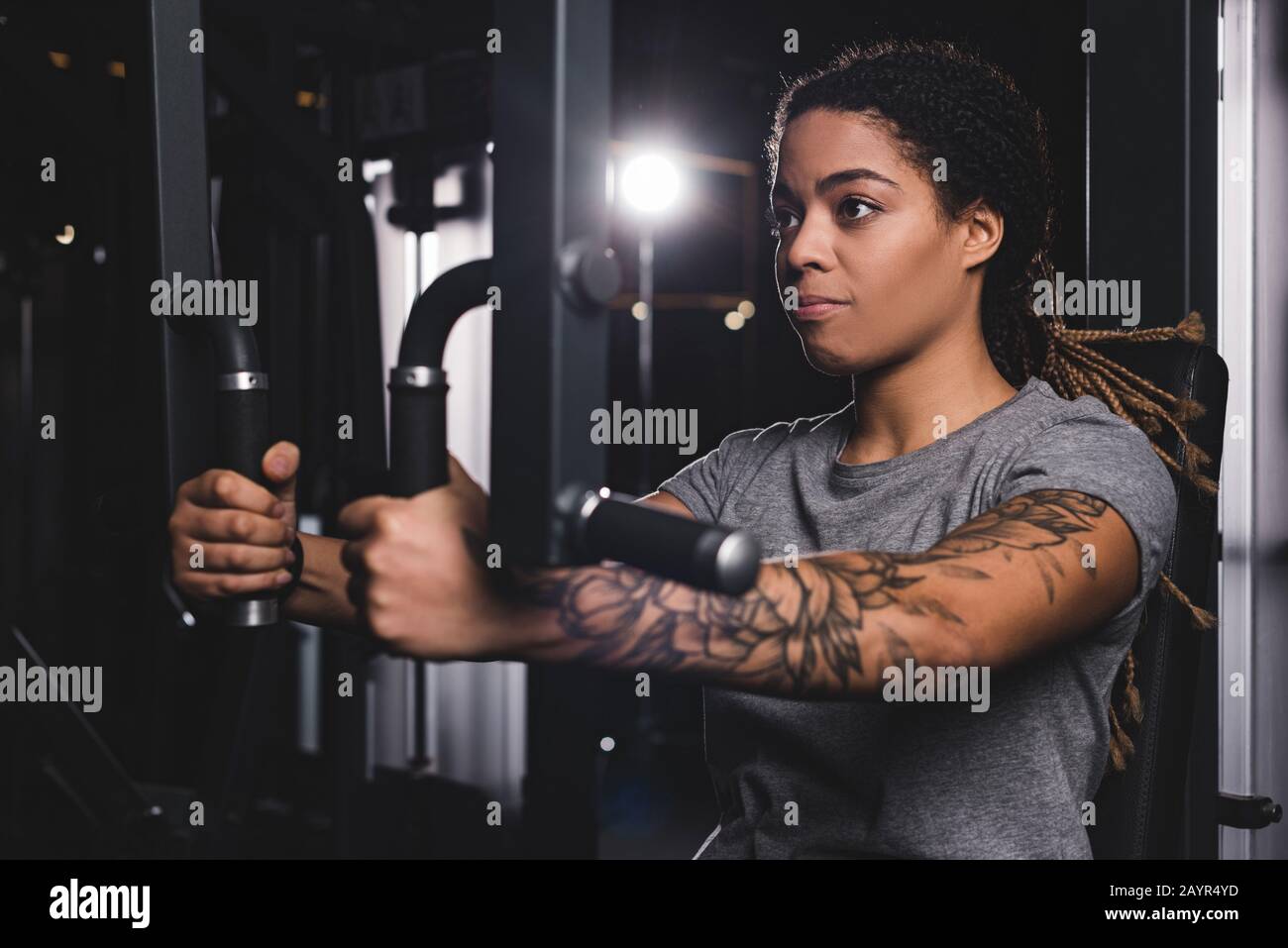 selective focus of young african american girl with tattoo training on gym  machine Stock Photo - Alamy