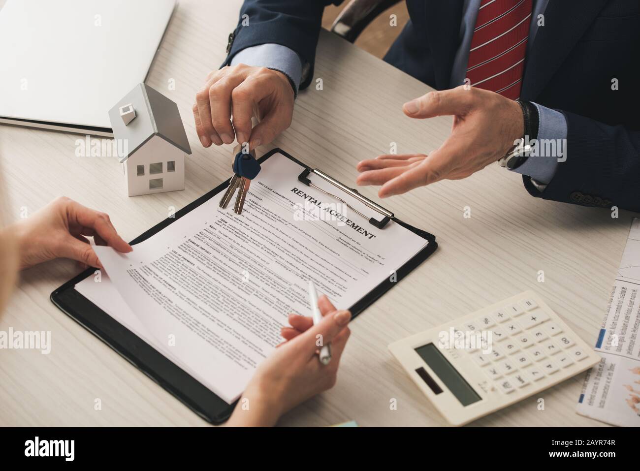 cropped view of woman near clipboard with rental agreement lettering and broker holding keys Stock Photo