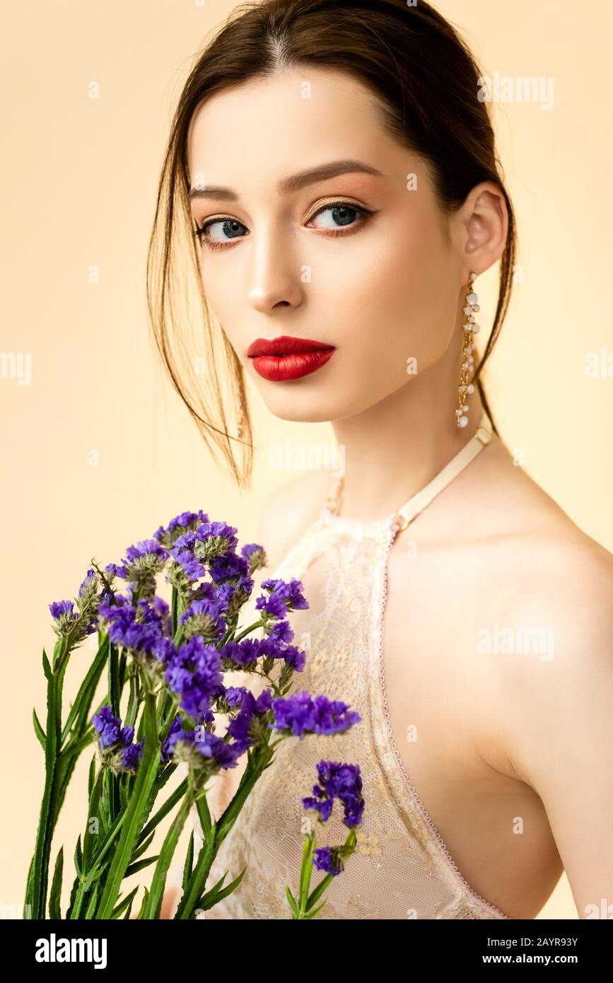 young attractive woman holding limonium flowers isolated on beige Stock Photo