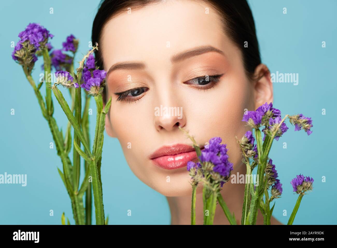beautiful woman looking at limonium flowers isolated on blue Stock Photo