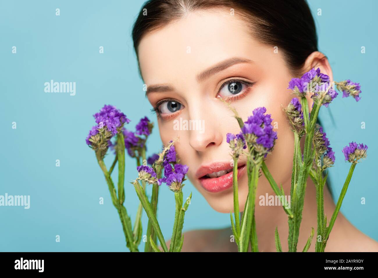 beautiful woman near limonium flowers isolated on blue Stock Photo