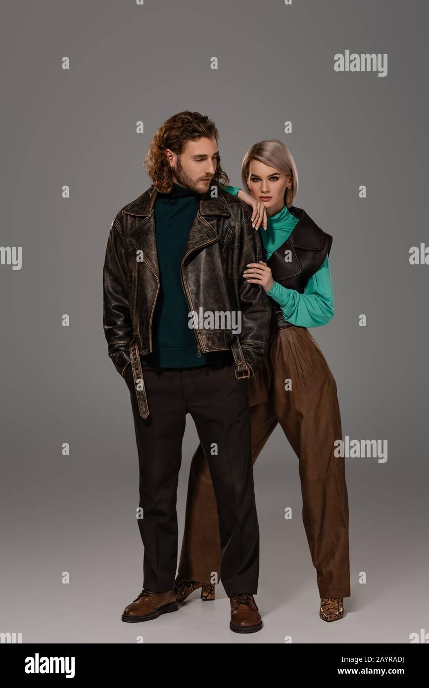 woman in vest hugging man in leather jacket on grey background Stock ...
